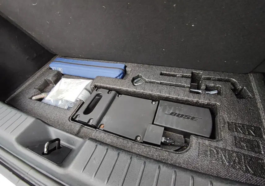 Rangement sous coffre montrant kit de bord et caisson Bose intégré du Mazda MX-30 gris clair électrique 2023.
