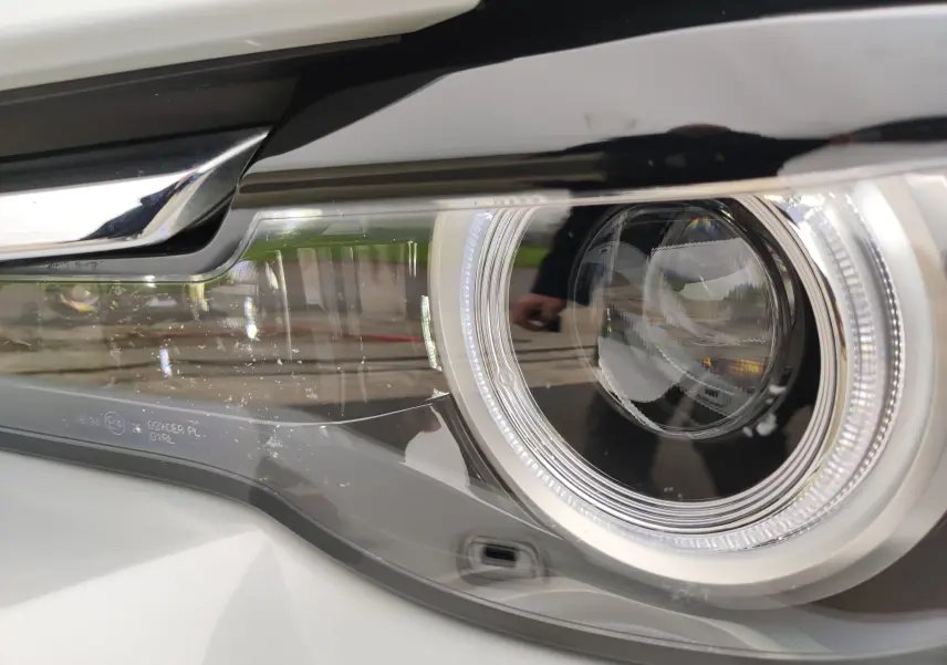 Gros plan sur le phare avant droit du Mazda MX-30 gris clair 2023, mettant en valeur son design LED circulaire.