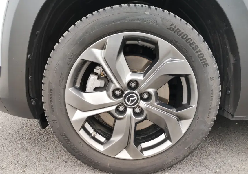 Gros plan sur la roue avant gauche gris clair d’un Mazda MX-30 2023 avec jante alliage et pneu Bridgestone.