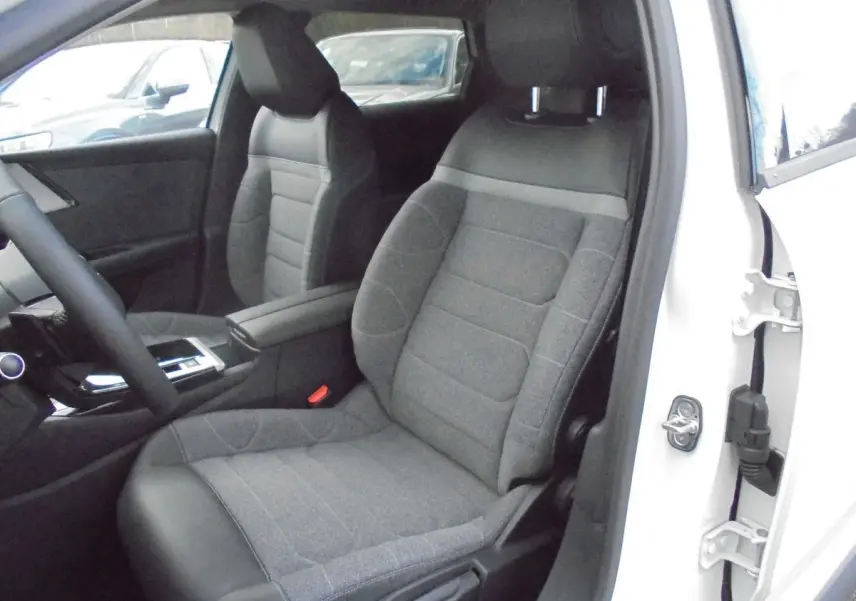 Vue intérieure côté conducteur d'une Citroën C5 X 2022 blanc nacré, siège avant en tissu gris avec appuie-tête intégré.