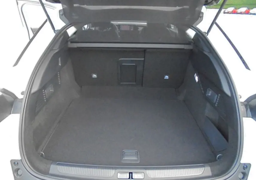 Coffre ouvert vu de l'arrière d'une Citroën C5 X blanc nacré, montrant un espace de chargement spacieux et propre.