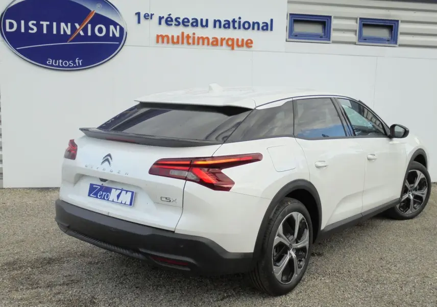Vue 3/4 arrière droite d'une Citroën C5 X blanche nacrée avec feux arrière LED et jantes alliage noires.