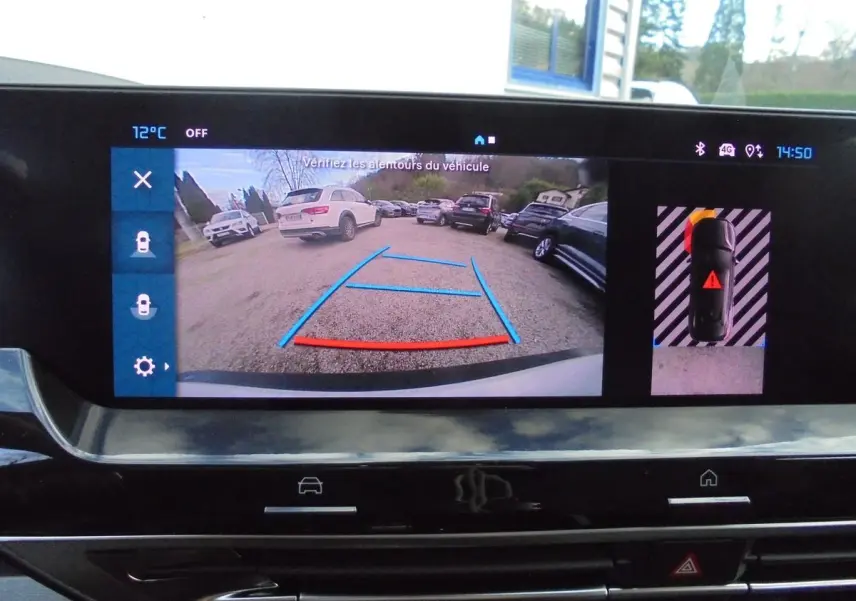 Écran intérieur de la Citroën C5 X blanc nacré montrant la caméra de recul et l'aide au stationnement active.