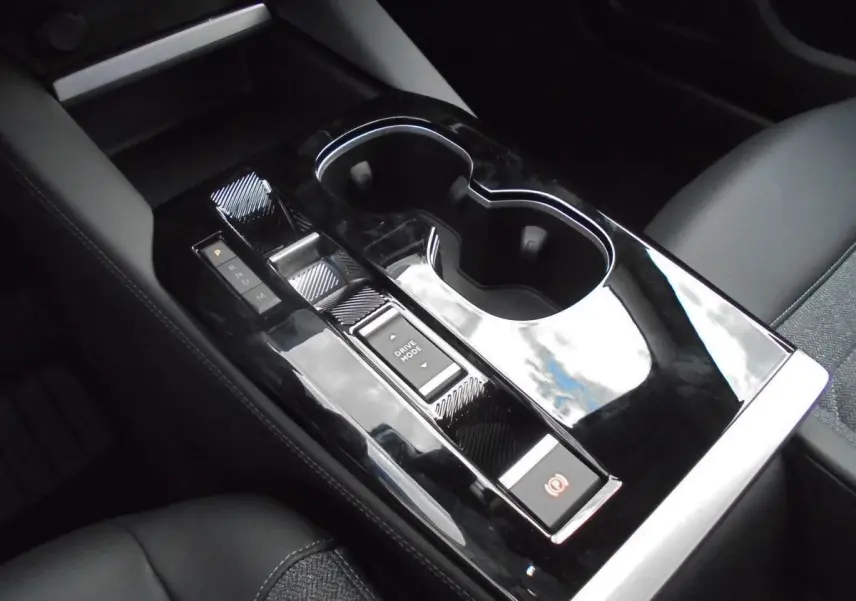 Gros plan sur la console centrale noire brillante de la Citroën C5 X 2022 avec commandes de boîte auto et porte-gobelets.