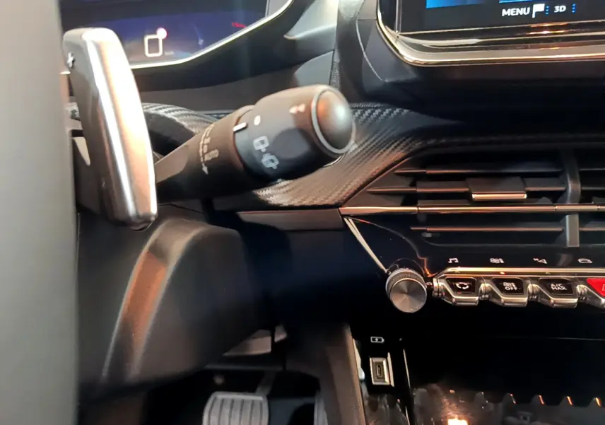 Détail intérieur côté gauche du tableau de bord et commandes de la Peugeot 208 gris foncé 2022 PureTech Allure Pack.