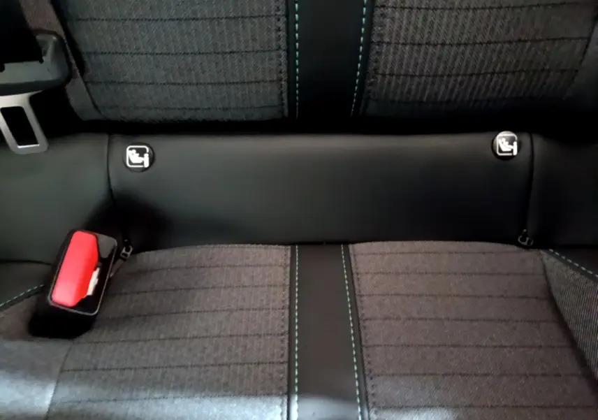 Vue rapprochée de la banquette arrière gris foncé de la Peugeot 208 avec coutures bleues et ancrages Isofix visibles.