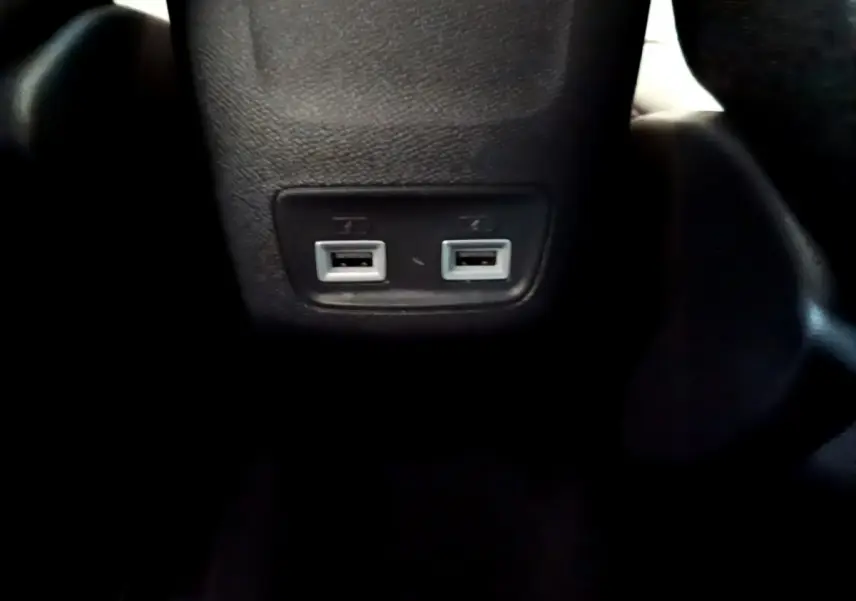 Gros plan sur les deux ports USB arrière intégrés dans le console centrale noire du Peugeot 208 gris foncé.