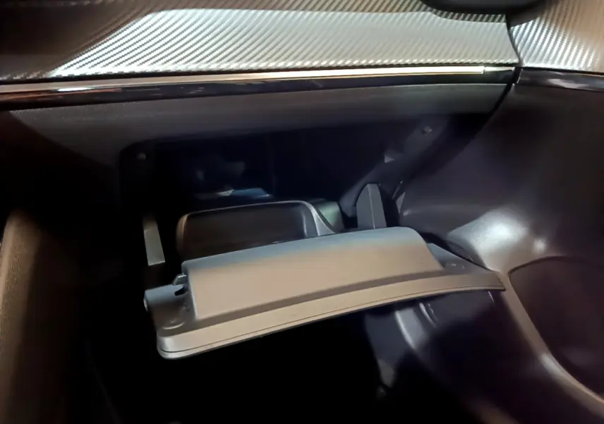 Vue rapprochée de la boîte à gants ouverte dans l’habitacle gris foncé de la Peugeot 208 PureTech 2022.