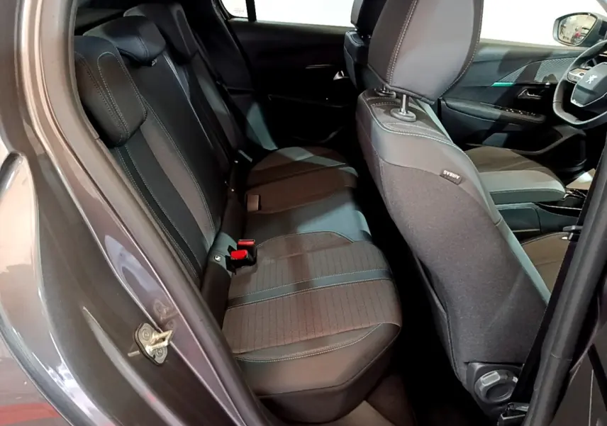 Vue intérieure côté gauche sur les sièges arrière et avant d’une Peugeot 208 gris foncé avec sellerie tissu et cuir.