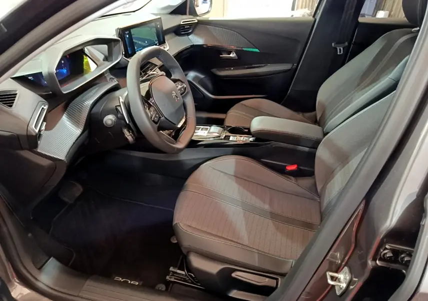 Intérieur avant droit de la Peugeot 208 gris foncé 2022, avec tableau de bord numérique et volant cuir multifonctions.