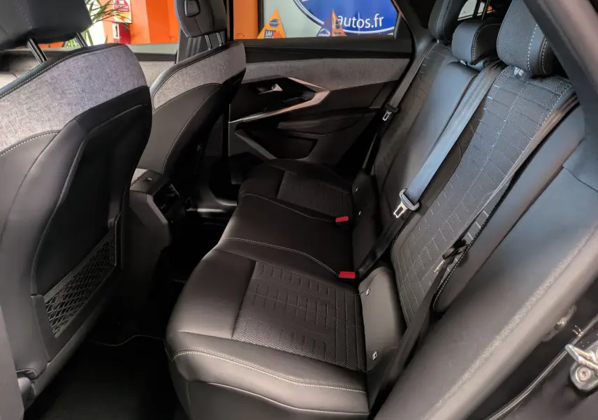 Vue latérale droite de l’arrière intérieur du Peugeot 3008 Hybrid 145 GT avec sièges en tissu et cuir noir à surpiqûres claires.