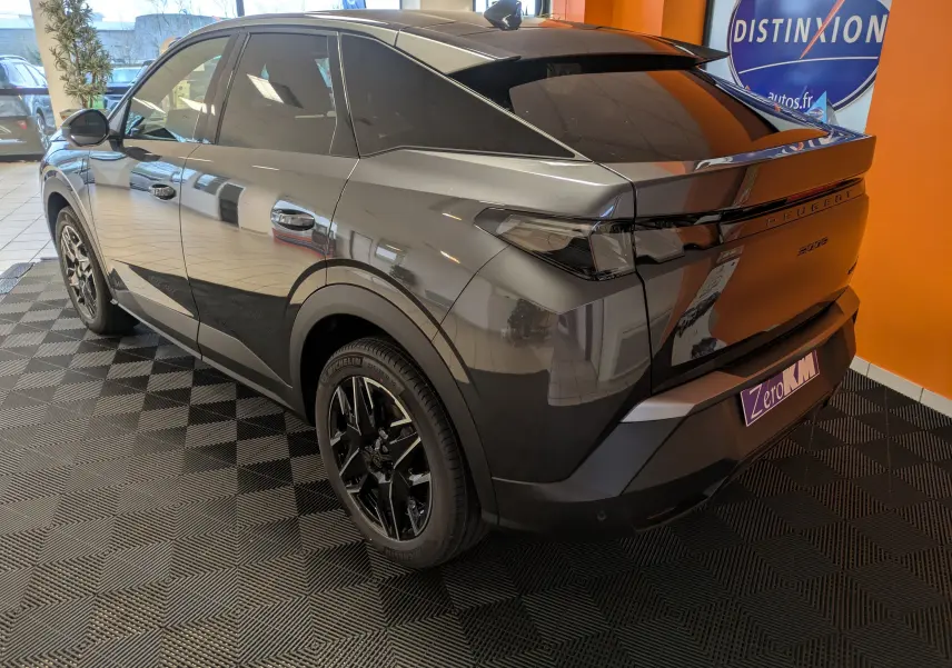Vue 3/4 arrière droite du Peugeot 3008 Hybrid gris titane avec toit noir et jantes alliage 19 pouces en intérieur showroom.