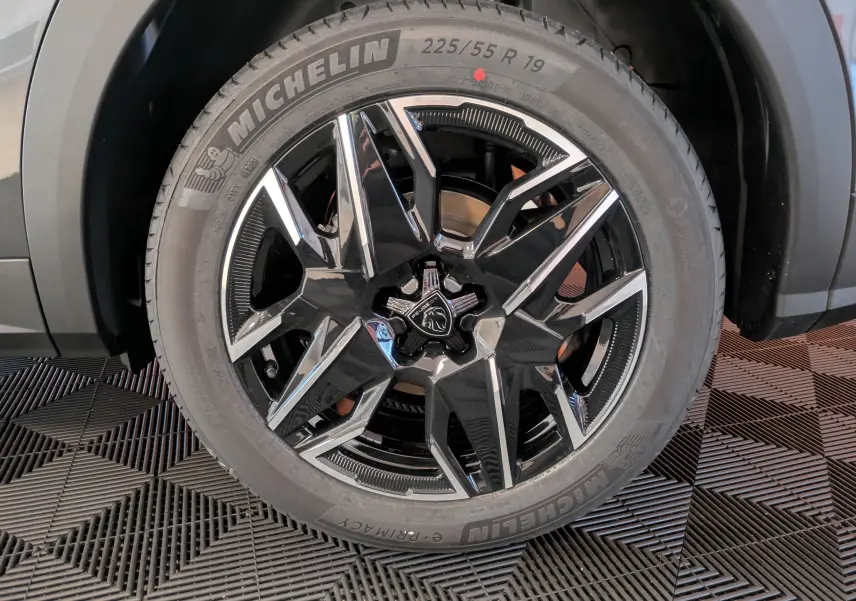 Gros plan sur la jante alliage 19 pouces noire et argentée du Peugeot 3008 Hybrid 145 GT gris titane, pneu Michelin visible.