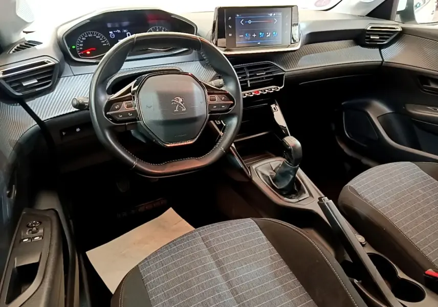 Intérieur de la Peugeot 208 1.2 PT 75 S&S Premium 2021, vue avant centrée sur le volant compact et l’écran tactile.