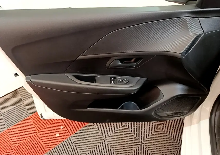 Vue intérieure de la porte avant gauche d'une Peugeot 208 blanche, avec commandes des vitres et revêtement noir texturé.