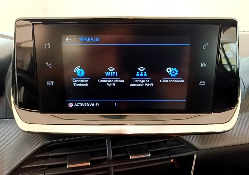 Écran tactile central du tableau de bord de la Peugeot 208 blanc, affichant les options de connexion Wi-Fi et Bluetooth.