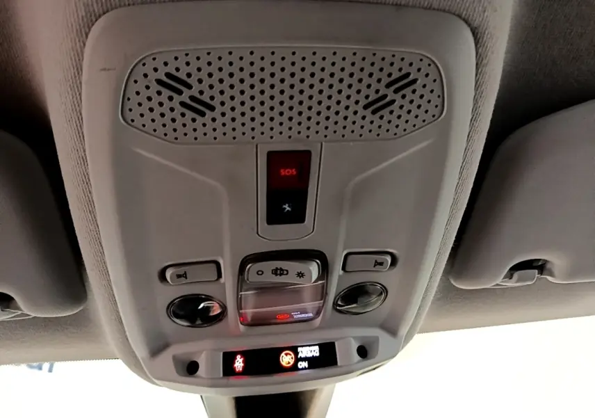Vue en contre-plongée du plafonnier gris avec bouton SOS et éclairage intérieur de la Peugeot 208 blanche.