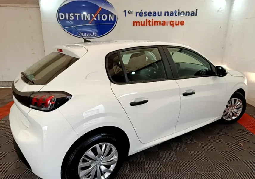 Peugeot 208 blanche vue 3/4 arrière droit en intérieur, avec feux arrière LED et jantes alliage visibles.