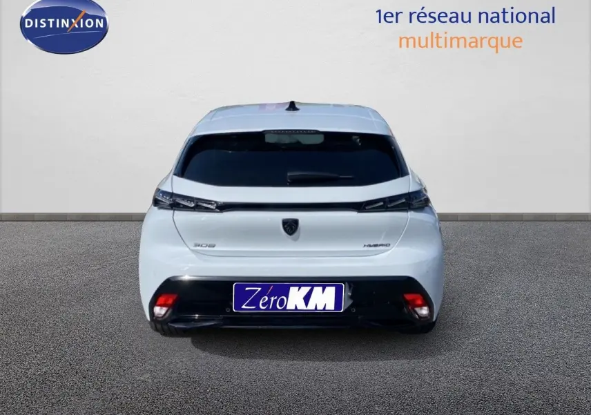 Vue arrière d'une Peugeot 308 blanche Okenite Hybrid 2026 avec feux effilés et logo noir central.