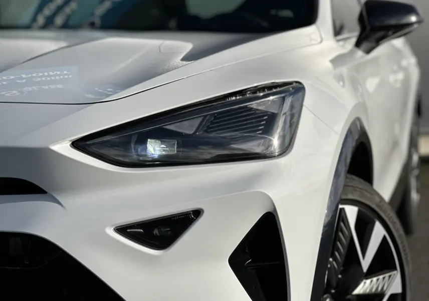 Gros plan sur l'avant droit blanc neige d'une CUPRA Formentor, mettant en valeur le phare Tri-LED et la jante alliage 19'' Sandstorm.