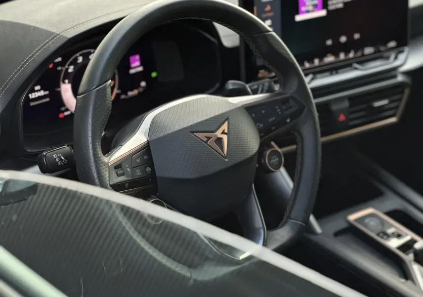 Vue rapprochée du volant cuir noir perforé avec logo CUPRA cuivré et tableau de bord numérique du Formentor 2025.