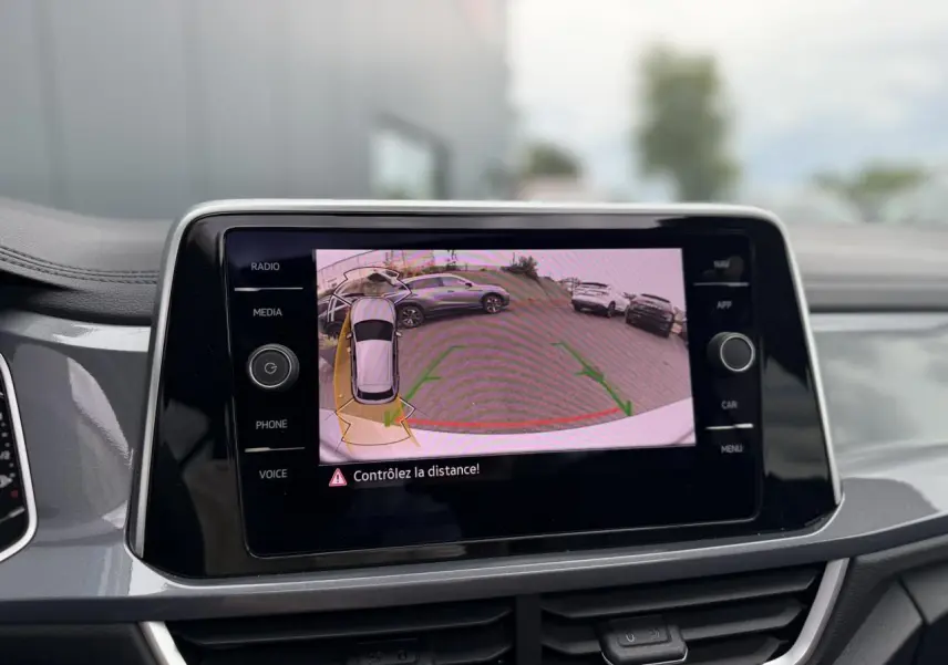 Écran tactile intérieur montrant la caméra de recul du Volkswagen T-Roc argenté, vue de face du tableau de bord.