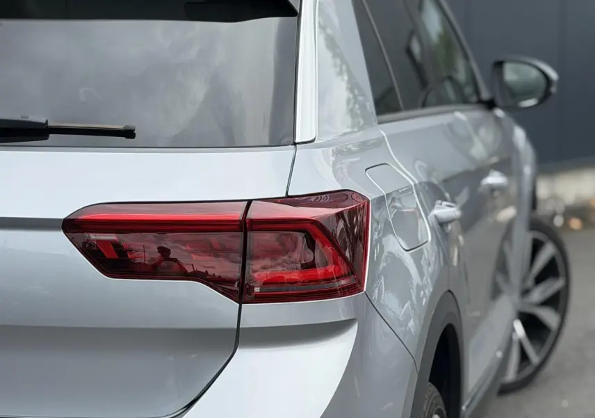 Vue 3/4 arrière droite du Volkswagen T-Roc 2024 argent pyrite avec feux arrière LED et jantes alliage 19 pouces.