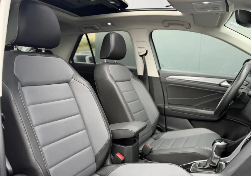 Vue intérieure des sièges avant en cuir gris platinium du Volkswagen T-Roc 2024 avec toit ouvrant panoramique.