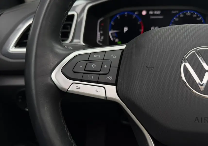 Gros plan sur le volant multifonction en cuir noir du Volkswagen T-Roc 2024, avec commandes de régulateur de vitesse.