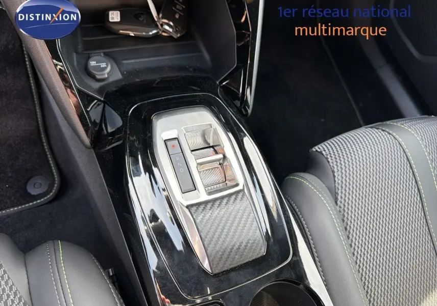 Gros plan sur la console centrale du Peugeot 2008 gris Artense, mettant en valeur la commande de boîte automatique et les sièges en cuir noir.