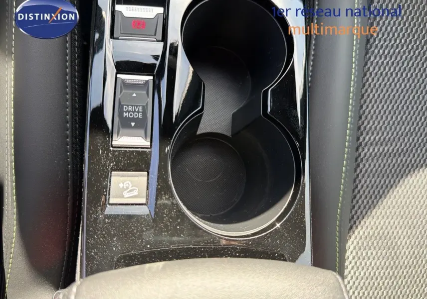 Gros plan sur la console centrale du Peugeot 2008 hybride 2026, montrant les porte-gobelets et les boutons Drive Mode.