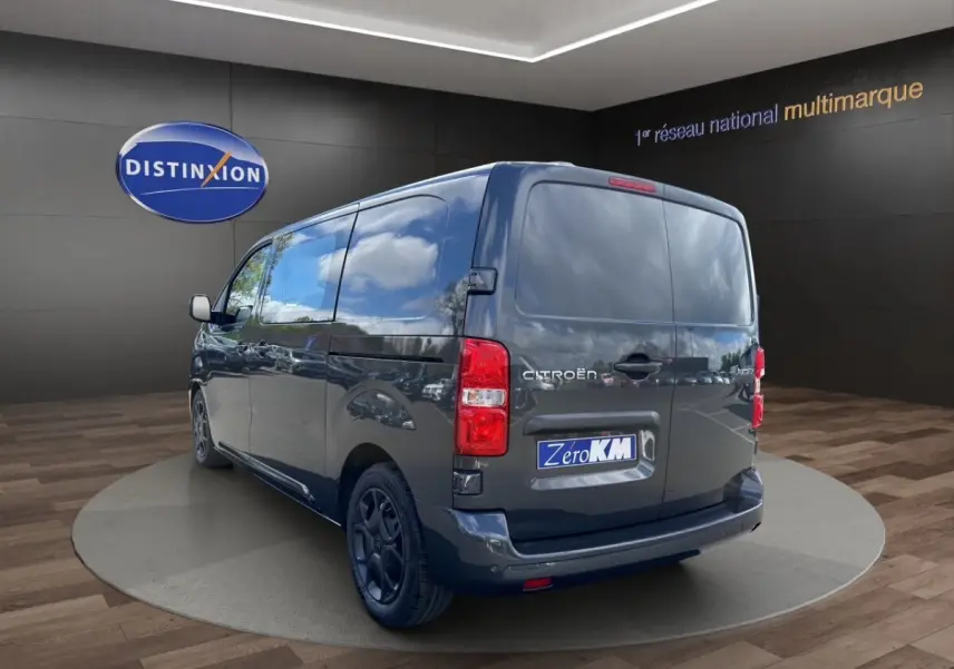 Vue 3/4 arrière droite d'un Citroën Jumpy gris foncé avec portes arrière pleines dans un showroom.