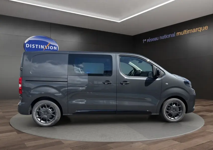 Vue de profil côté gauche d’un Citroën Jumpy gris foncé avec vitres teintées et jantes noires.