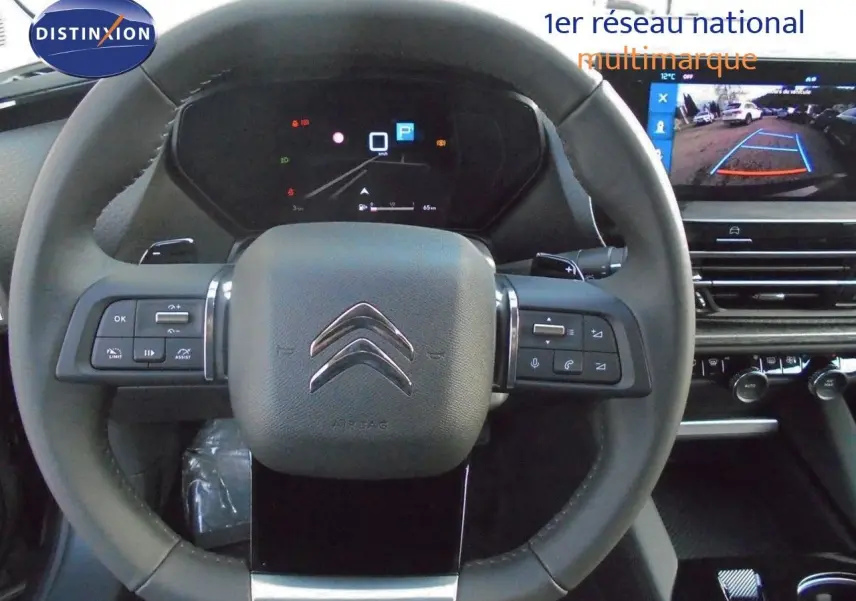 Volant cuir du Citroën C5 X 2022 avec commandes intégrées et écran affichant la caméra de recul en arrière-plan.