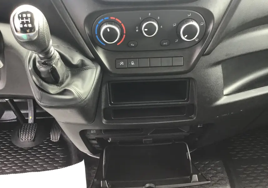 Intérieur du tableau de bord de l'Iveco Daily Fourgon 2022, avec levier de vitesses manuel et commandes de climatisation.