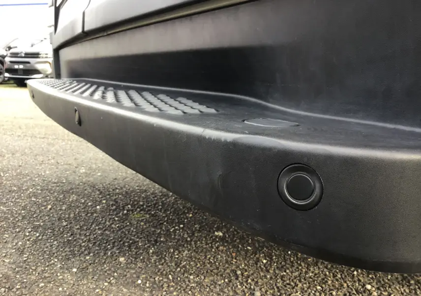 Gros plan sur le marchepied arrière noir du fourgon blanc Iveco Daily 35S16, soulignant le capteur de recul intégré.