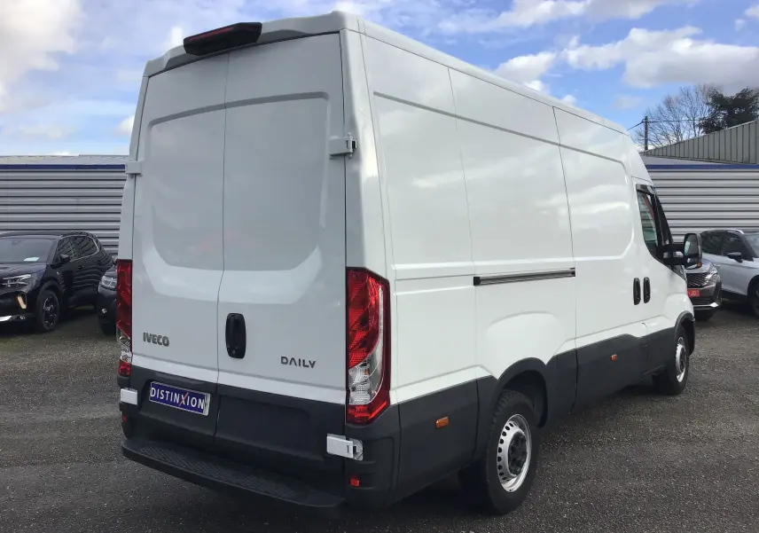 Vue 3/4 arrière droite d'un fourgon Iveco Daily blanc avec marchepied arrière et feux arrière rouges.