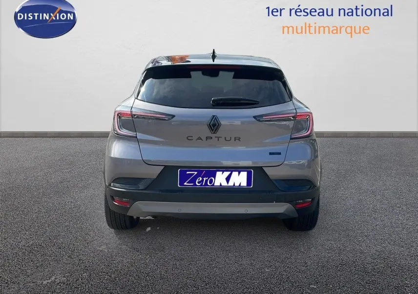 Vue arrière d'un Renault Captur gris cassiopée métal avec toit noir, modèle hybride 2025, sur fond neutre.