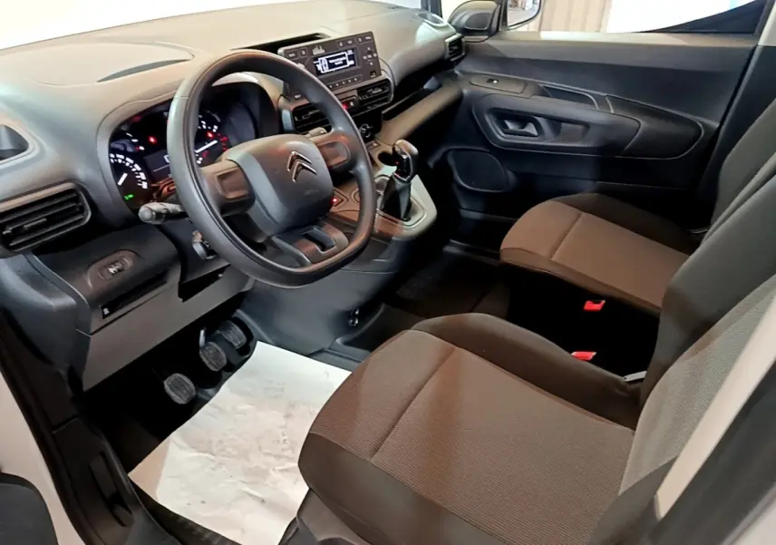 Intérieur côté conducteur du Citroën Berlingo 2021, volant, tableau de bord et sièges en tissu marron visibles.
