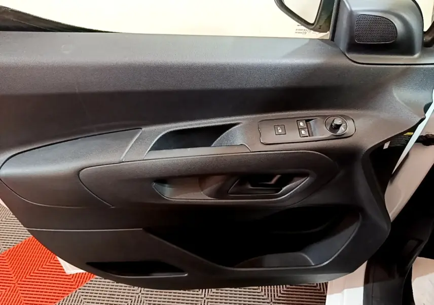 Gros plan sur la porte avant gauche noire du Citroën Berlingo blanc, avec commandes de vitres et rétroviseur électrique.
