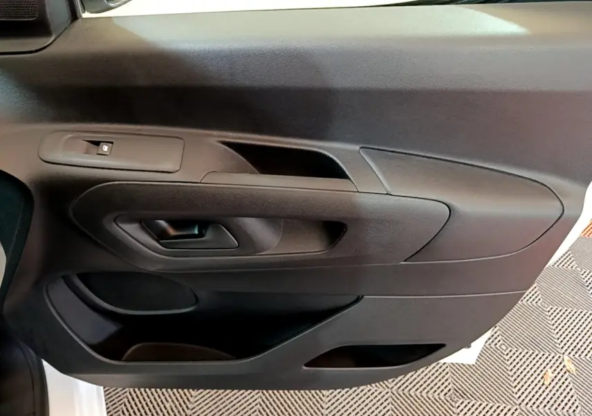 Vue rapprochée de la porte intérieure côté gauche du Citroën Berlingo blanc, avec poignée et commande de vitre.