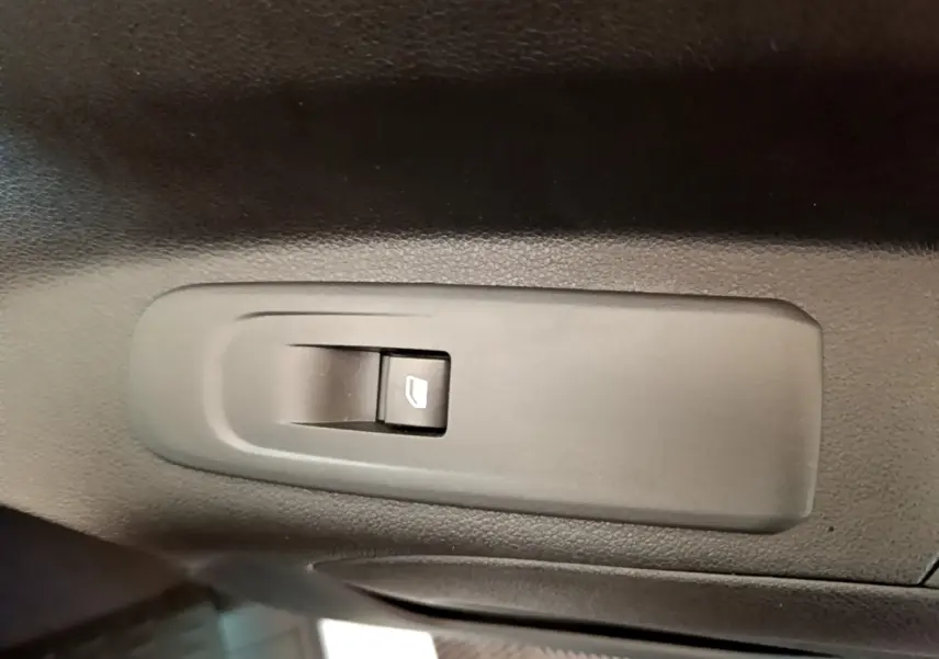 Gros plan sur le bouton de commande de vitre électrique noir dans l'habitacle du Citroën Berlingo blanc.
