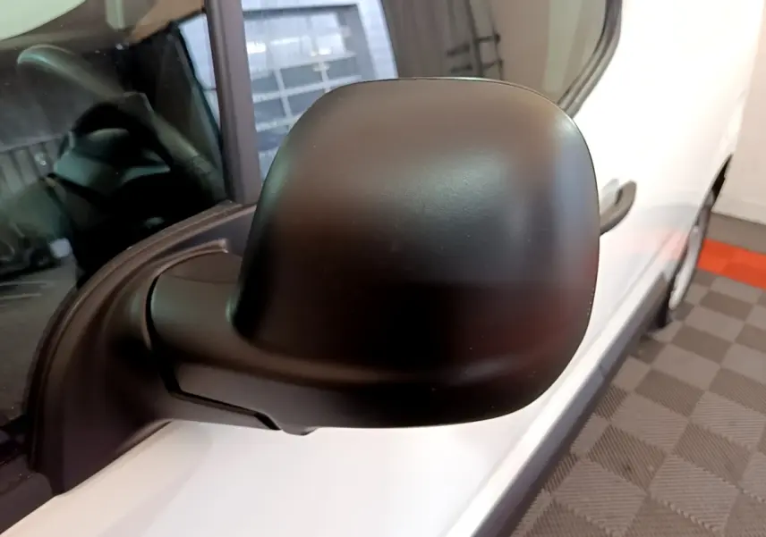Rétroviseur noir en gros plan côté gauche du Citroën Berlingo blanc, vue rapprochée sur la portière avant.