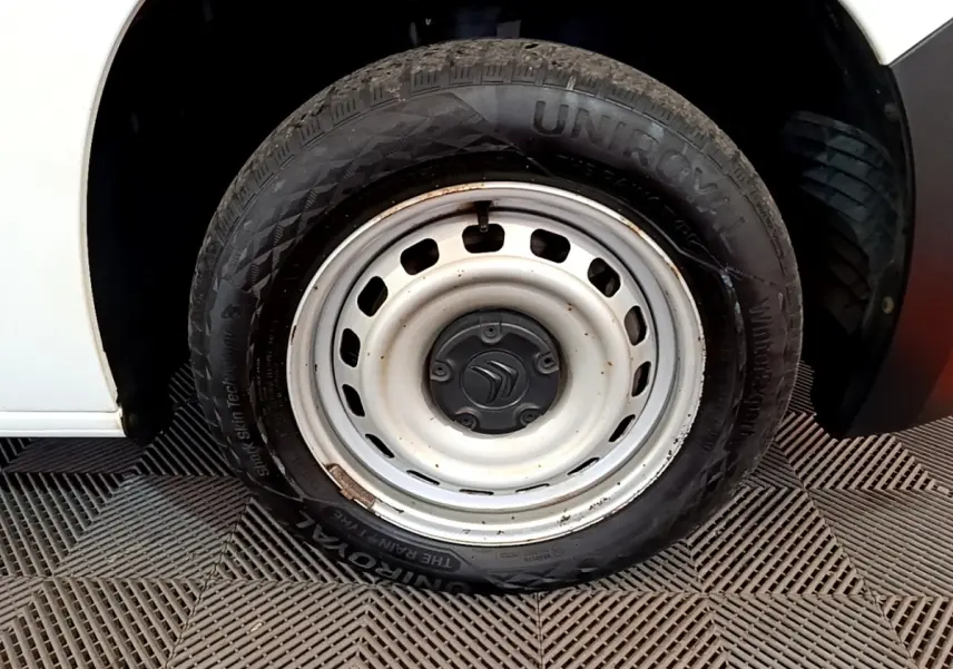 Gros plan sur la roue acier blanche avant droite d’un Citroën Berlingo blanc, avec logo Citroën au centre.