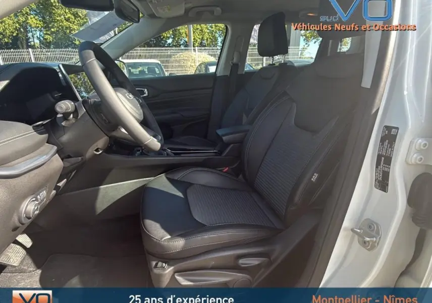 Vue intérieure côté conducteur du Jeep Compass blanc 2024, mettant en valeur le siège en cuir noir et l'accoudoir central.