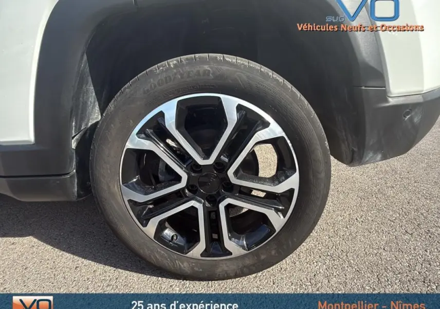 Gros plan sur la roue avant droite d’un Jeep Compass blanc 2024 avec jante alliage 18 pouces bicolore.