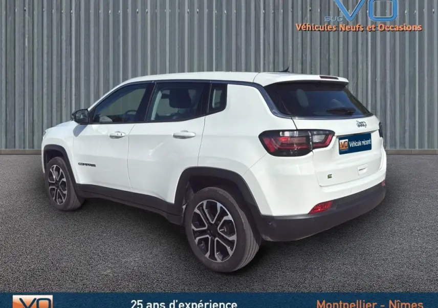 Jeep Compass blanc vue 3/4 arrière côté droit, jantes alliage 18 pouces et vitres teintées visibles.