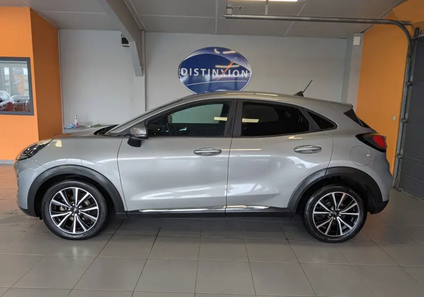 Vue de profil côté gauche d’un Ford Puma gris 2020 avec jantes alliage bicolores et poignées de porte chromées.