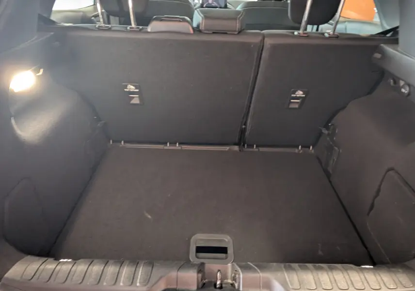 Coffre ouvert de la Ford Puma gris, vue intérieure arrière montrant le tapis de coffre et les dossiers de sièges rabattus.