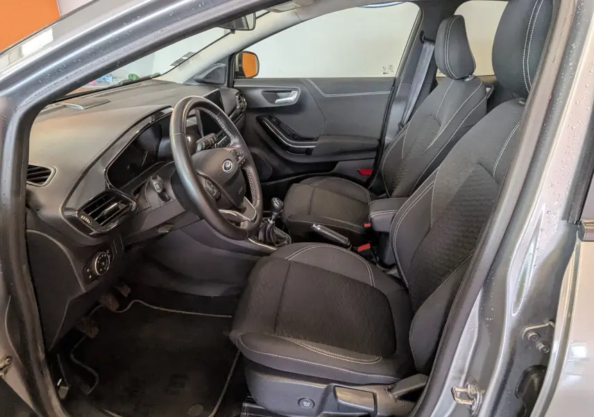 Vue intérieure côté conducteur du Ford Puma gris 2020, montrant sièges noirs et tableau de bord avec volant multifonction.